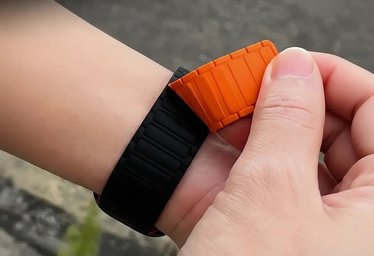 Close-up of a wrist wearing a black and orange smartwatch band.