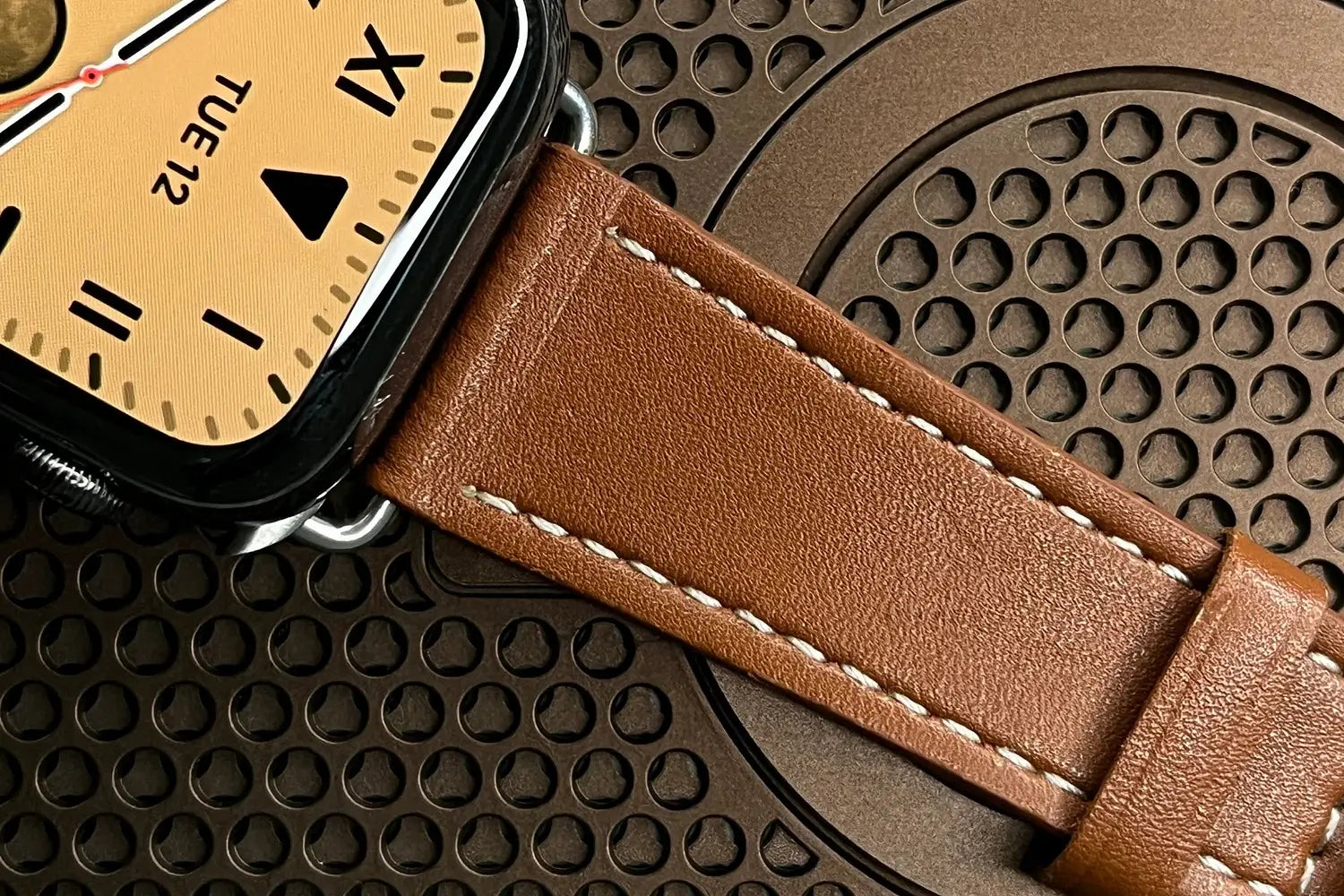 Smartwatch with a brown leather strap on a textured surface