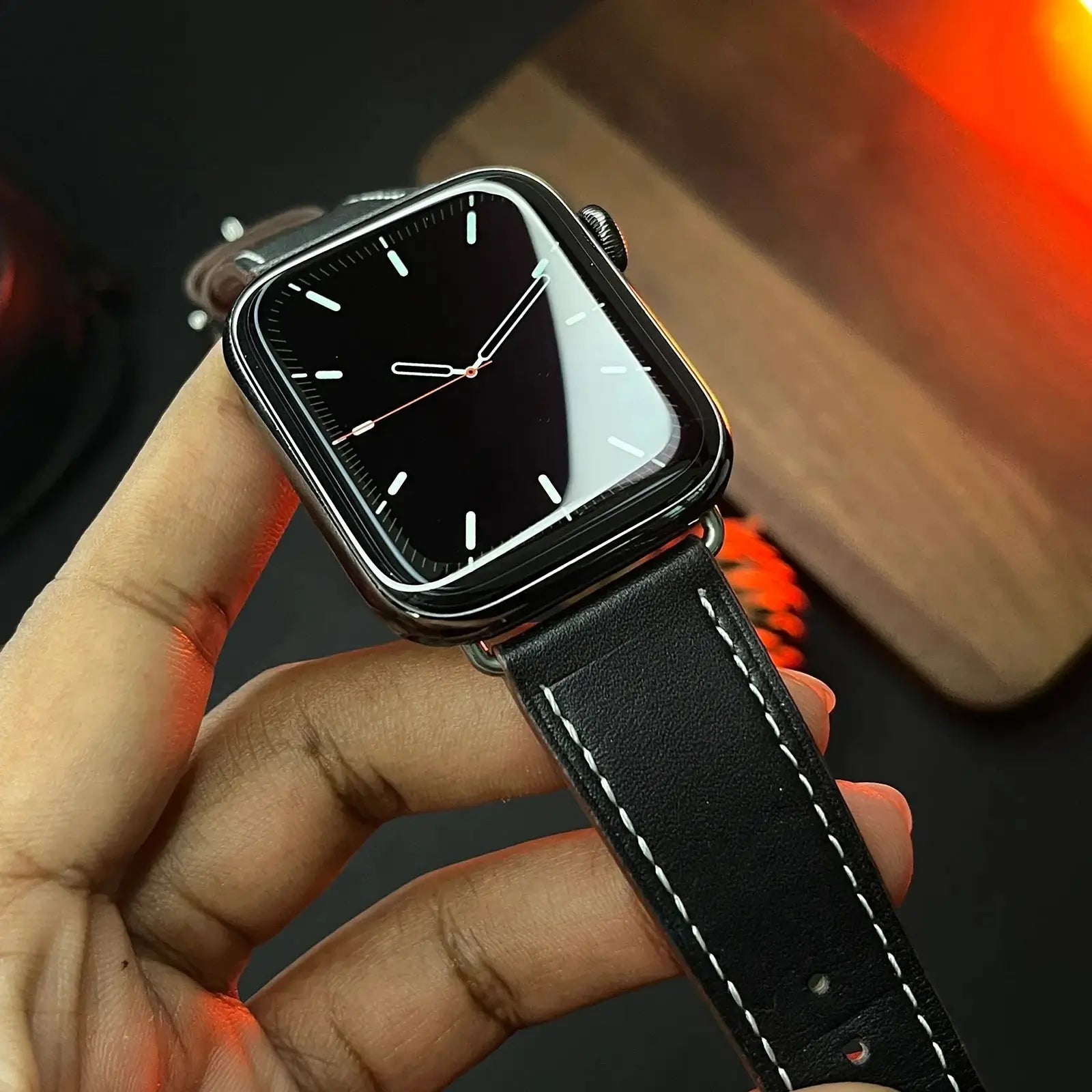Black smartwatch held in a hand against a blurred background