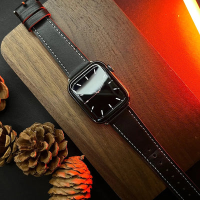 Smartwatch with a black strap on a wooden surface with pine cones.