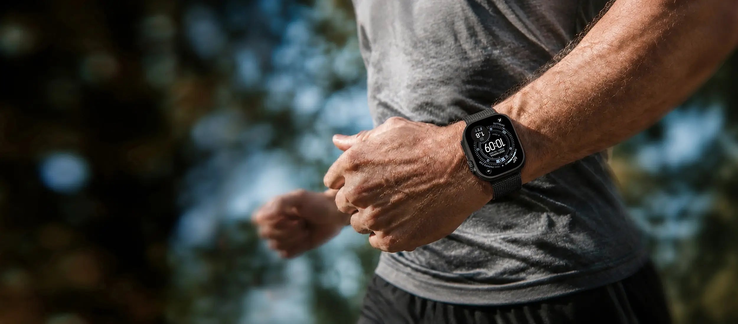 A close-up lifestyle shot of a man jogging outdoors, wearing a black smartwatch on his wrist.