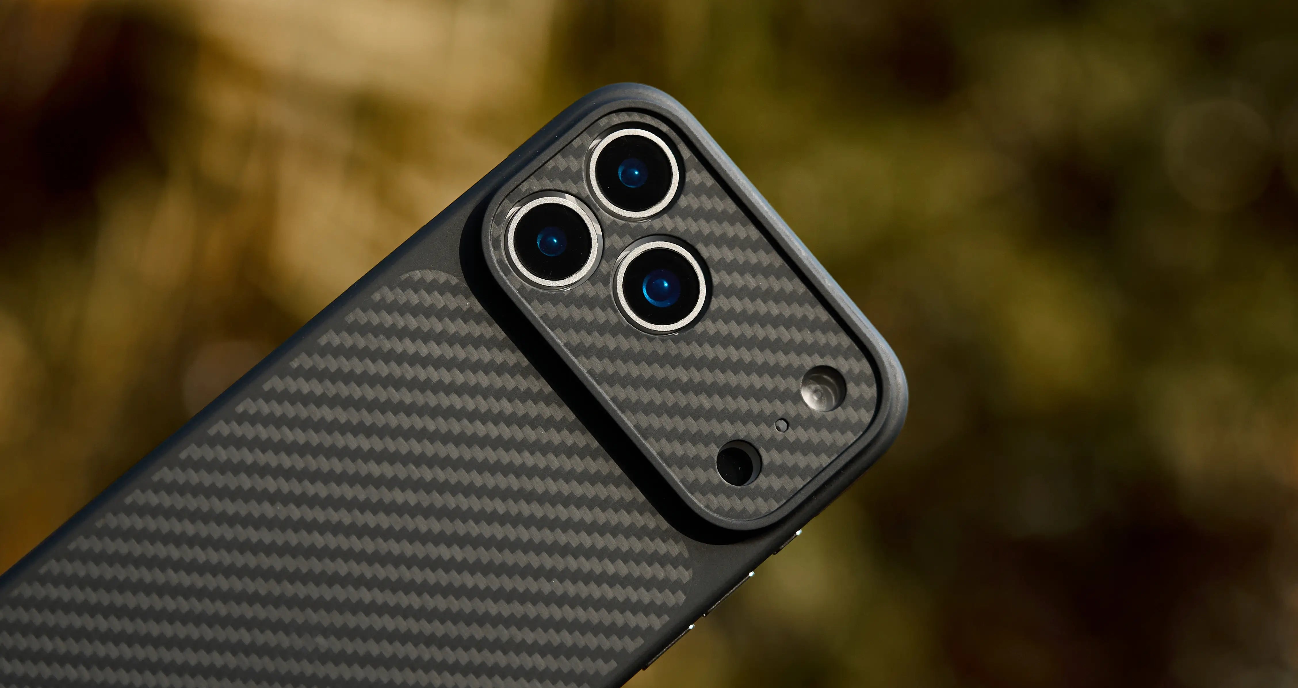 Phone case with carbon fiber texture on a blurred natural background
