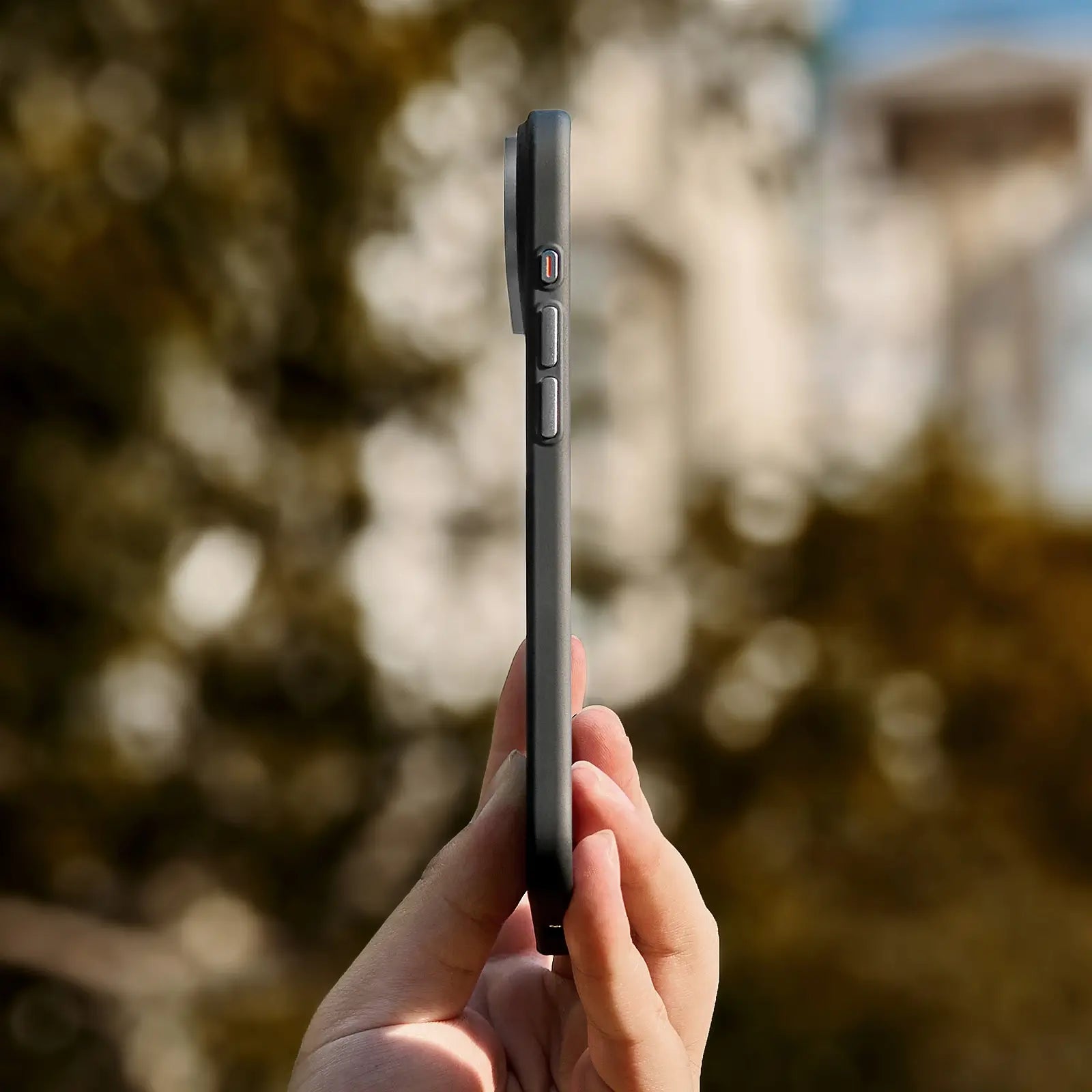 Hand holding a smartphone with a blurred natural background