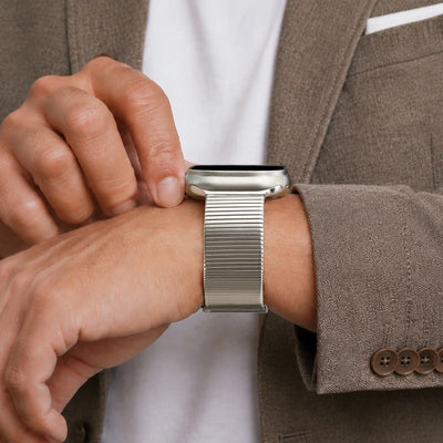 Person wearing a silver smartwatch on their wrist with a brown suit jacket.