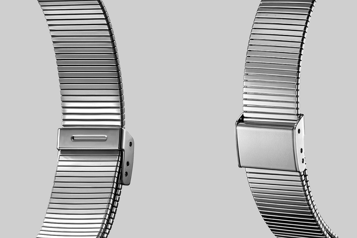 Two metallic watch straps on a light gray background