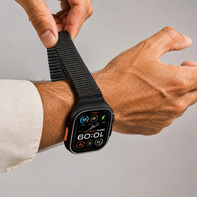 Person adjusting a black smartwatch on their wrist with a gray background