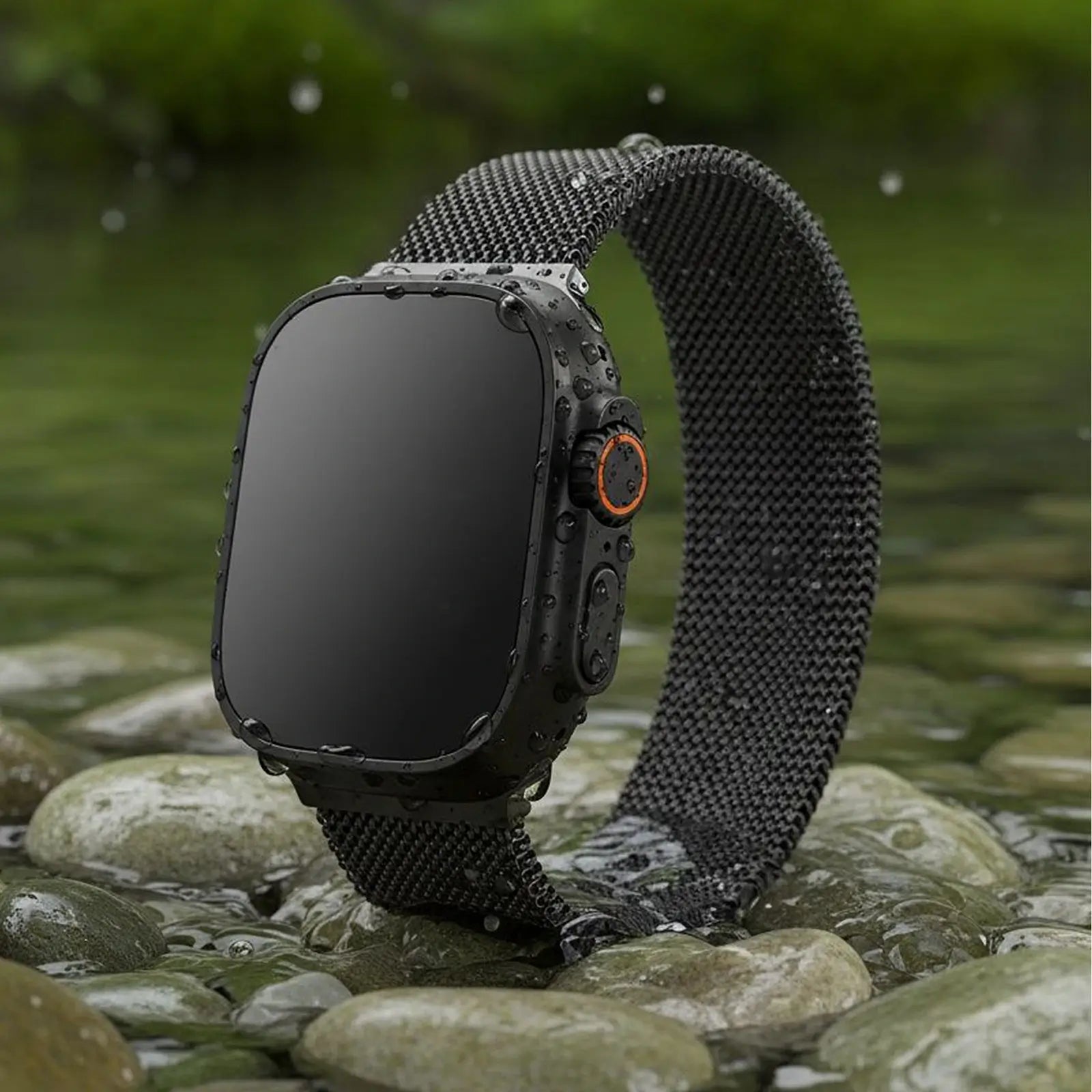 Smartwatch with a black mesh band on a rocky surface with water in the background