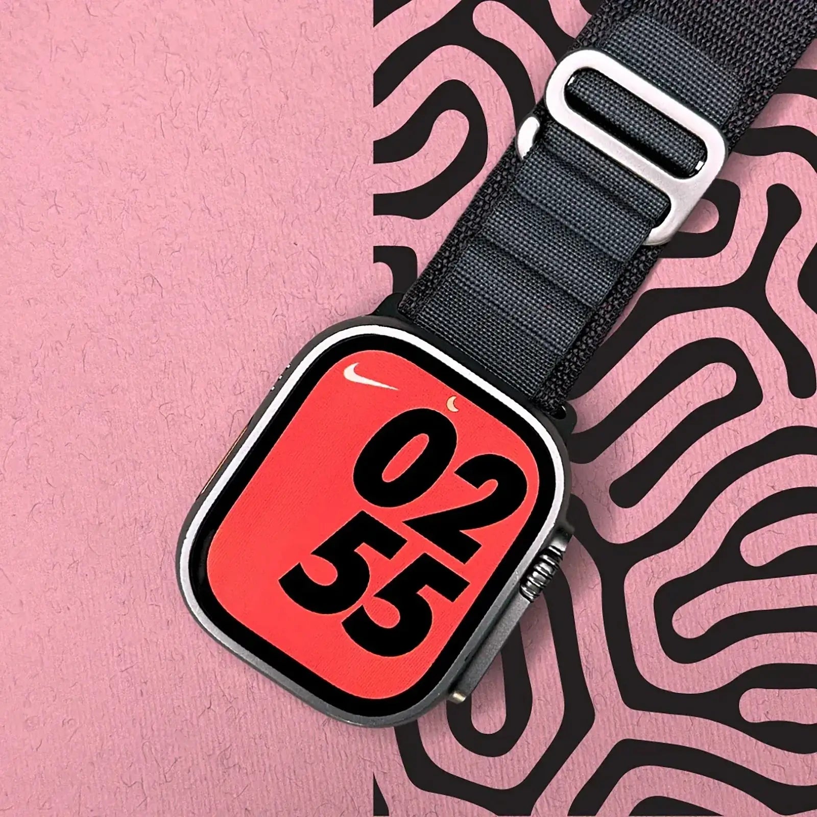 Black strap with a red and black '0235' label on a pink and black patterned background