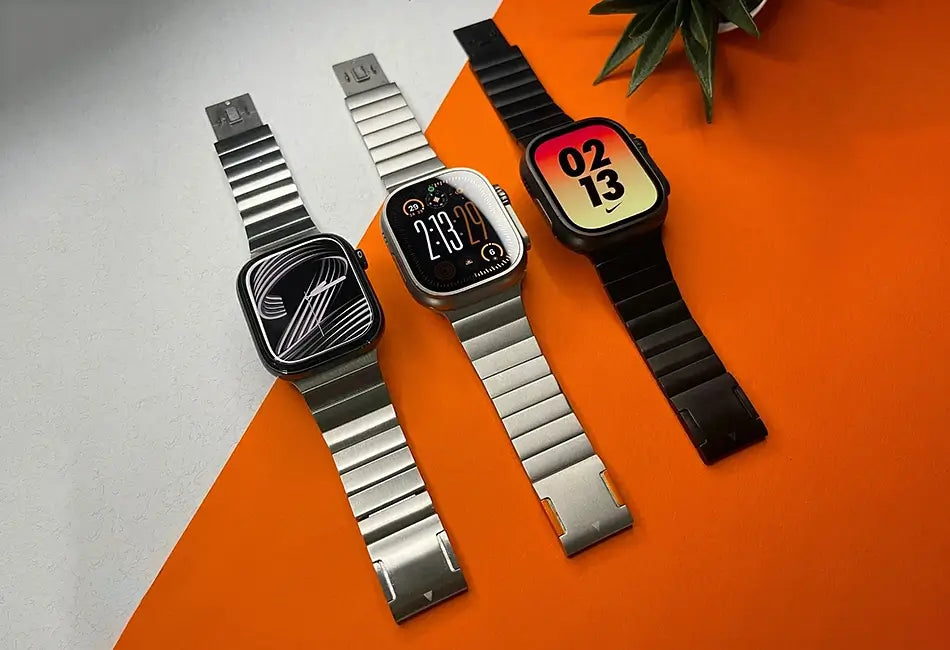 Three smartwatches with different band colors on an orange surface.