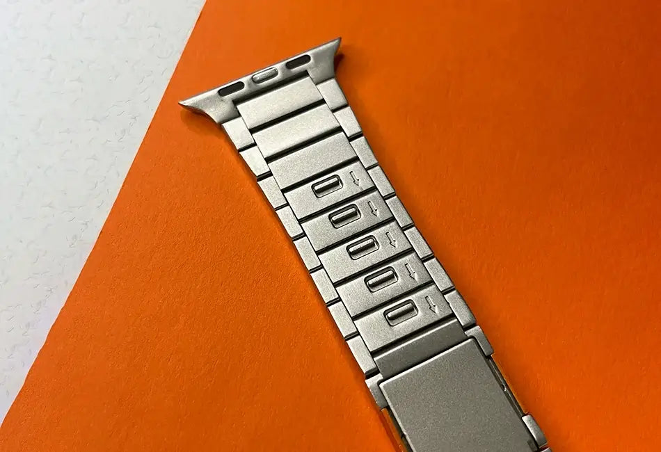 Silver metal watch strap on an orange and white background
