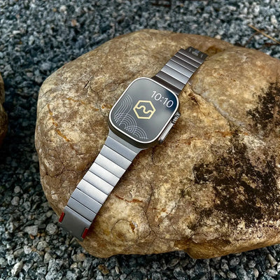Silver smartwatch on a rock with a textured background