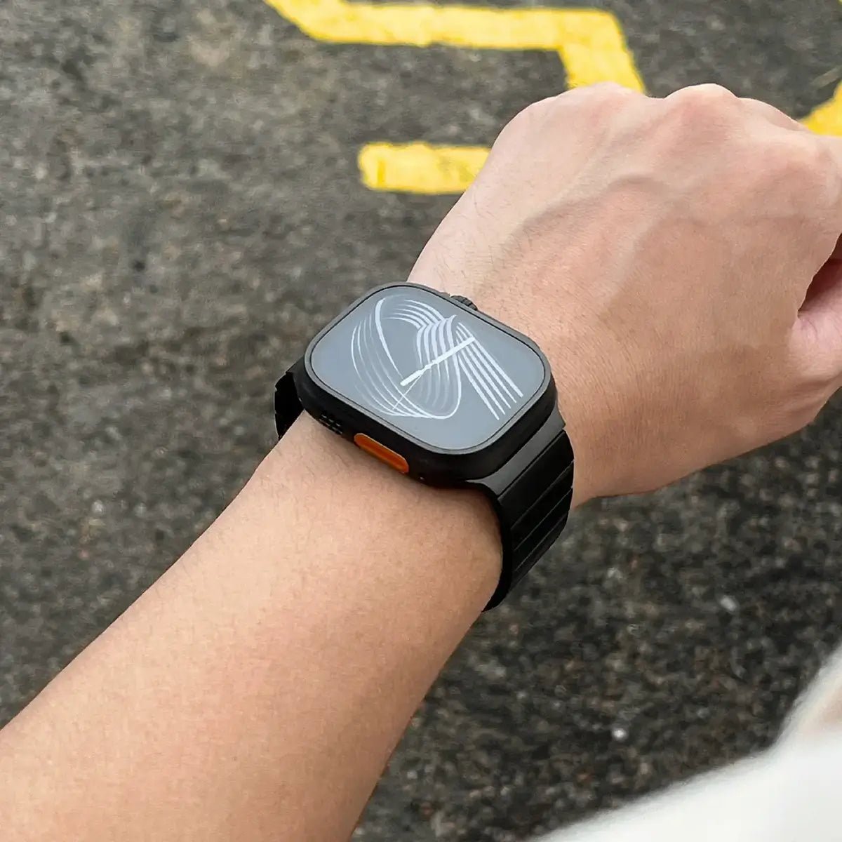 Person wearing a black smartwatch on a textured surface